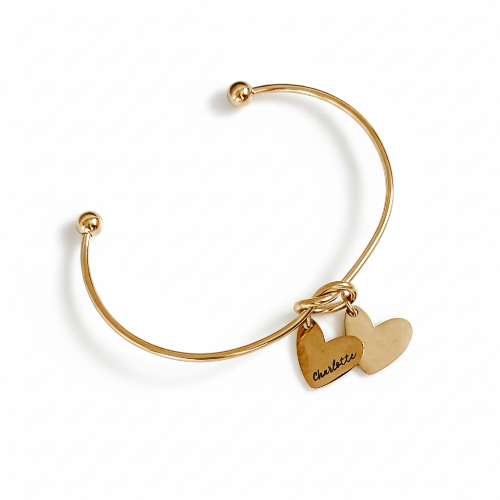 Gold bangle with heart-shaped charms on a marble surface